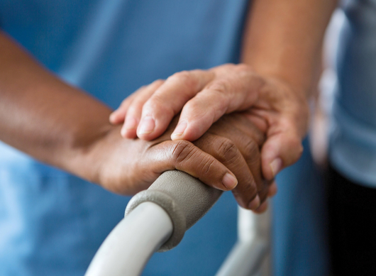 Hands of nurse and senior woman holding walker